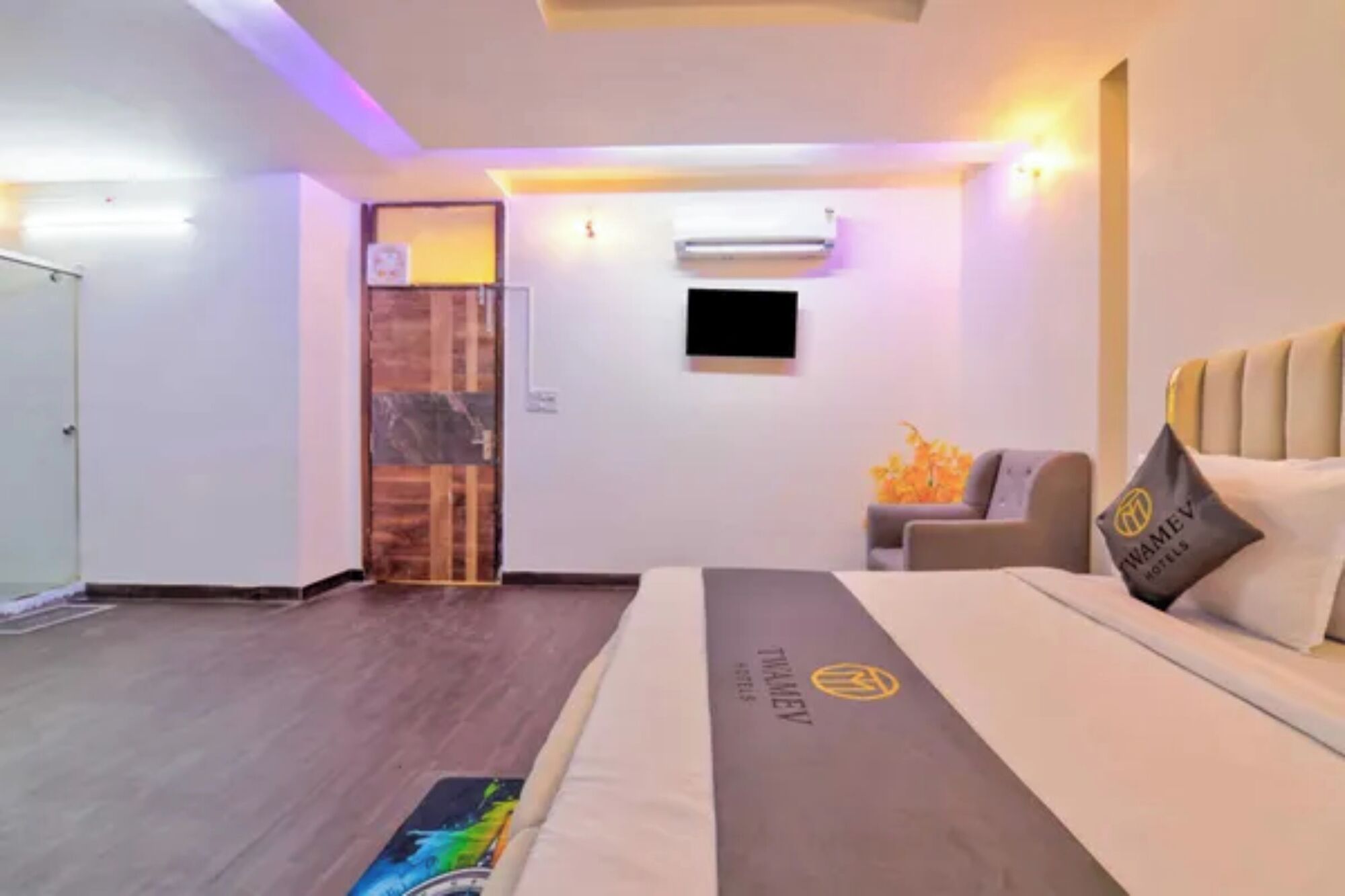 A hotel room with a bed, a sofa, a TV, and a door.