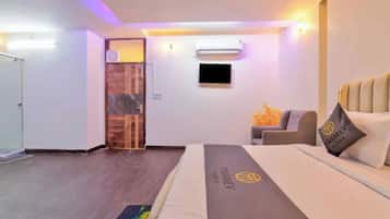 A hotel room with a bed, a sofa, a TV, and a door.