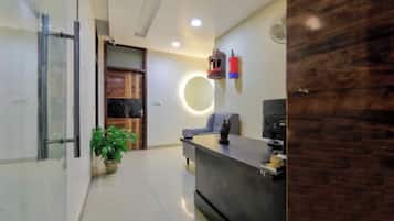 A reception area with a desk, a potted plant, a circular light fixture, and a fire extinguisher.