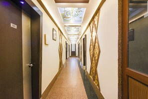 Um corredor de hotel com claraboia, obras de arte emolduradas e uma porta com o número 103.