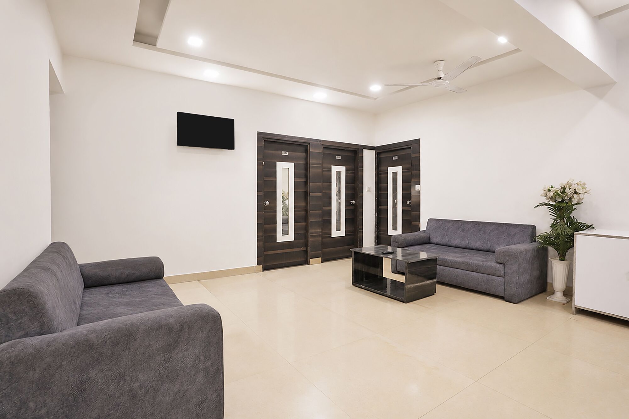 Un área de espera moderna con un sofá, una mesa de centro y un mostrador de recepción.