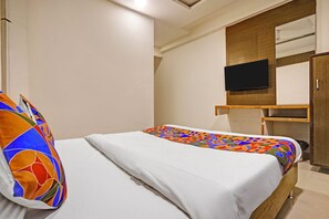 A hotel room with a bed, a television mounted on the wall, and a wooden cabinet. - Fabhotel Mid Way (Gandhinagar)