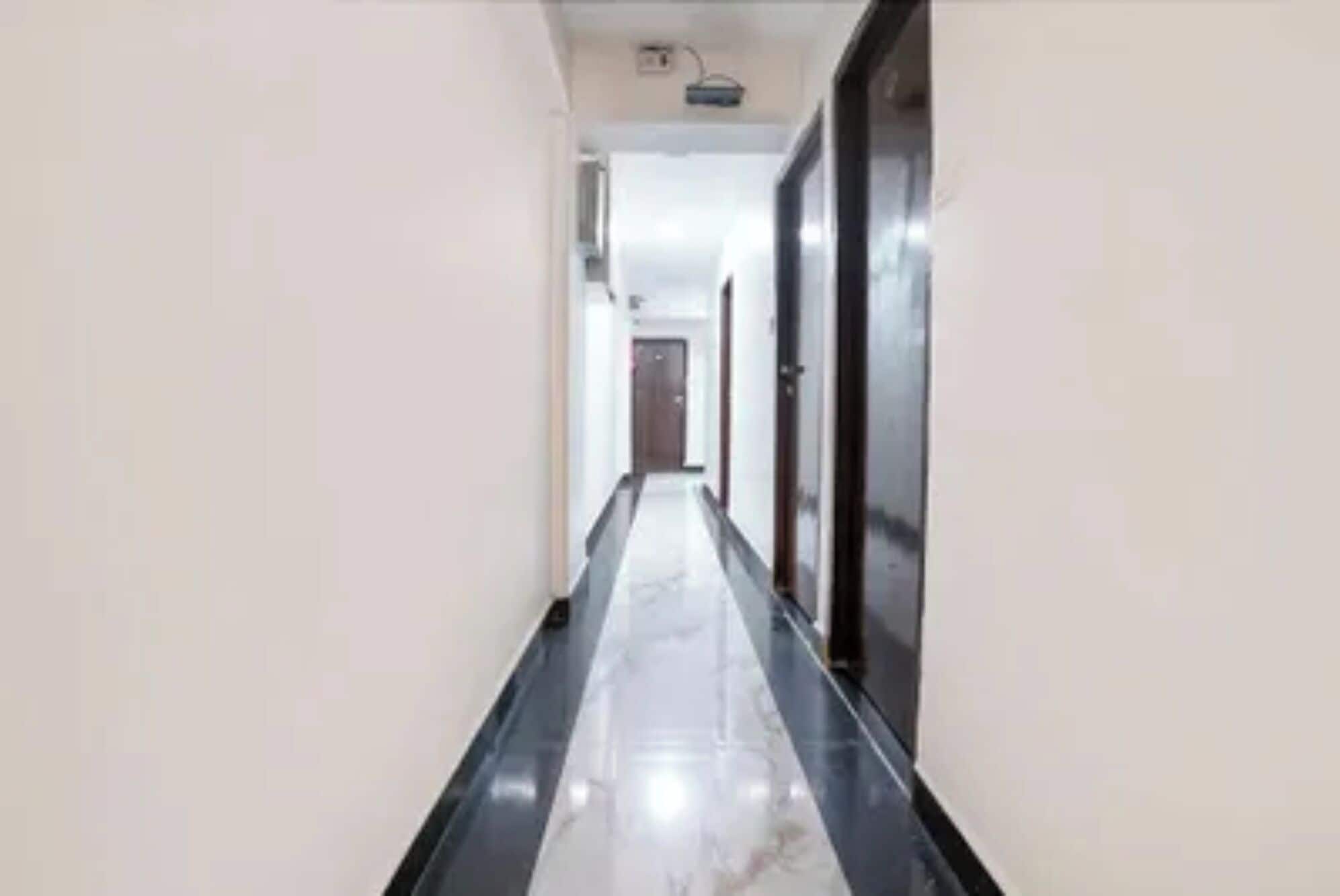 A corridor with a marble floor and a door at the end.