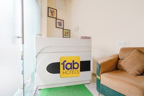 Un mostrador de recepción de hotel con un logotipo, un sofá y una alfombra verde.