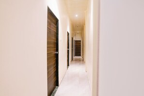 Un pasillo estrecho con puertas de madera a un lado y una pared lisa al otro.