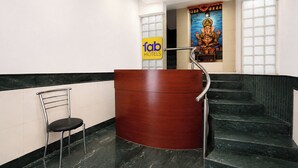 Vestíbulo de hotel con una escalera de mármol, una silla y un cartel que dice 'fab hotels'.