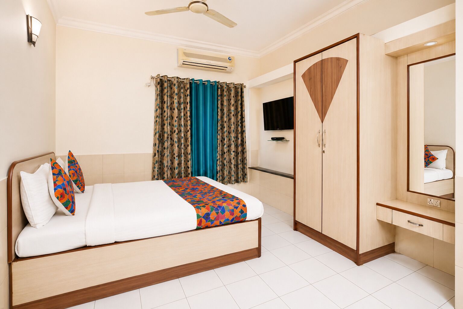 A hotel room with a bed, a wardrobe, a television, and a mirror.