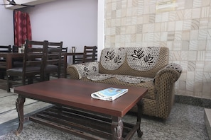 A living room with a brown sofa, a wooden coffee table, and a patterned wall. - FabHotel Maharaja Palace (Haridwar)