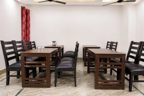 Un comedor con suelo de mármol, mesas y sillas de madera y un ventilador de techo.