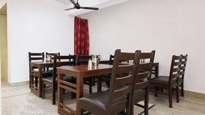 Un comedor con una mesa redonda y seis sillas, un ventilador de techo y una cortina roja.