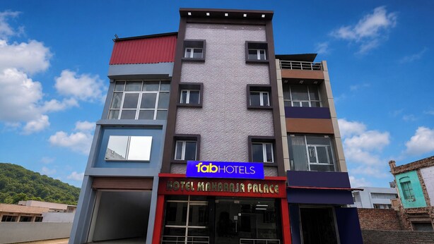 Un hotel de varios pisos con un letrero que indica 'Fab Hotels' y 'Hotel Maharaja Palace' en la planta baja.