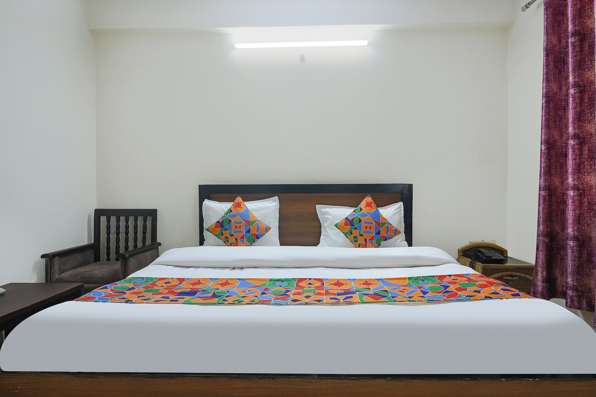 A hotel room with a bed, a nightstand, a telephone, and a curtain.