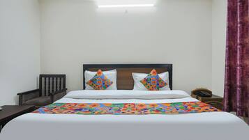 A hotel room with a bed, a nightstand, a telephone, and a curtain.