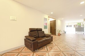 A hotel lobby with a brown leather sofa, a patterned floor, and a door leading to another room. - FabHotel Akshaya Bheemas Inn (Penumuluru)