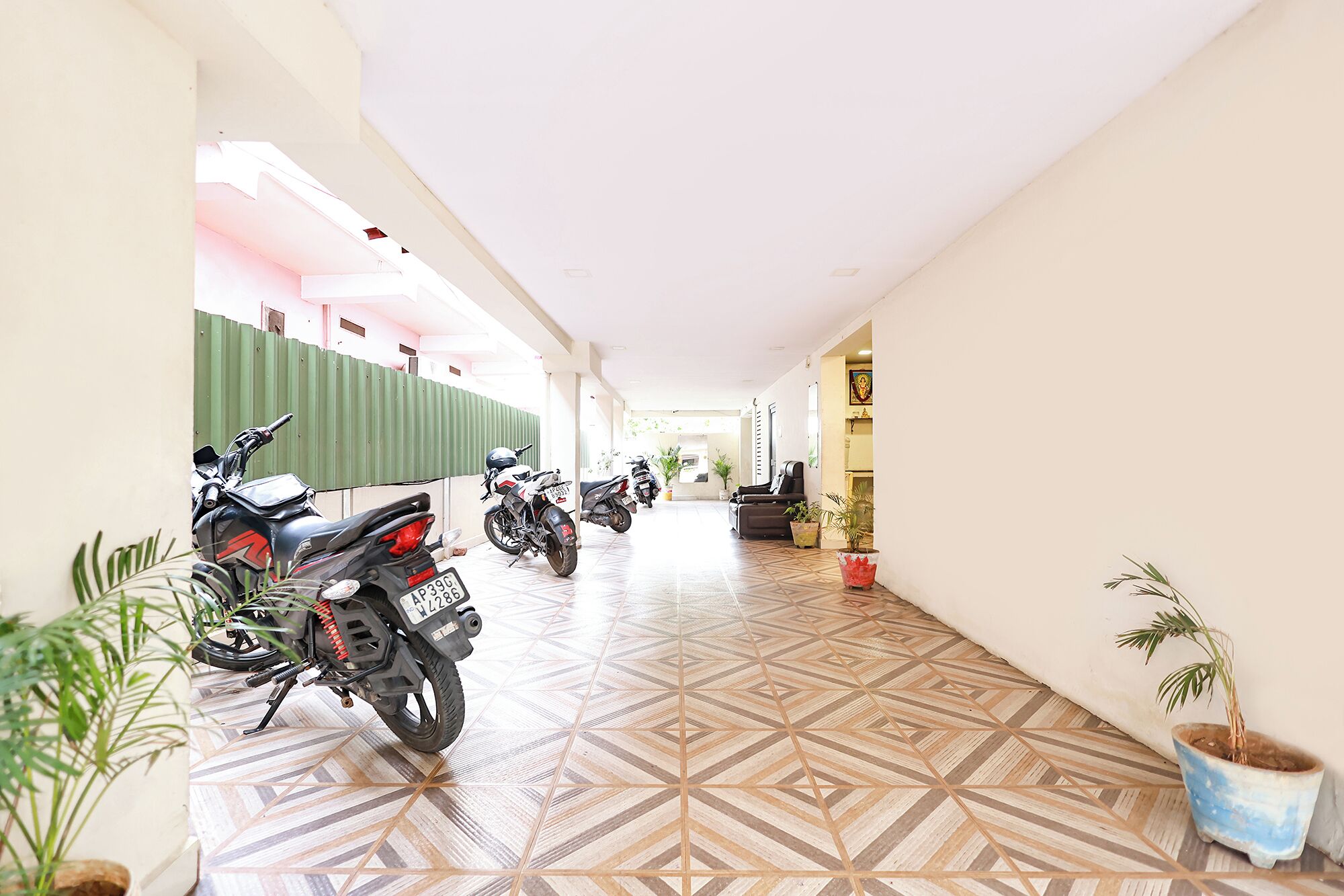 A corridor with tiled flooring, parked motorcycles, and potted plants.
