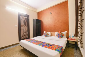 Une chambre d’hôtel comprenant un lit, une table de chevet, une armoire et une lampe fixée au mur.