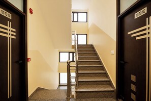 Un escalier avec des marches recouvertes de moquette et des rampes en métal, menant à l’étage supérieur.