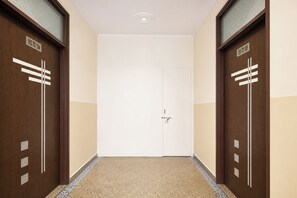 A hallway with two doors labeled '103 TO 104' and '105 TO 106' leading to a white door with a keyhole. - FabHotel Singh Guest House (New Delhi)