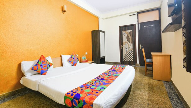 A hotel room with a bed, a desk, a chair, and a wardrobe.