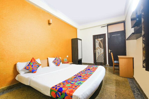 A hotel room with a bed, a desk, a chair, and a wardrobe.