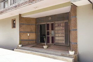 A building entrance with a metal gate, two potted plants on the steps, and a sign reading 'Singh House'. - FabHotel Singh Guest House (New Delhi)