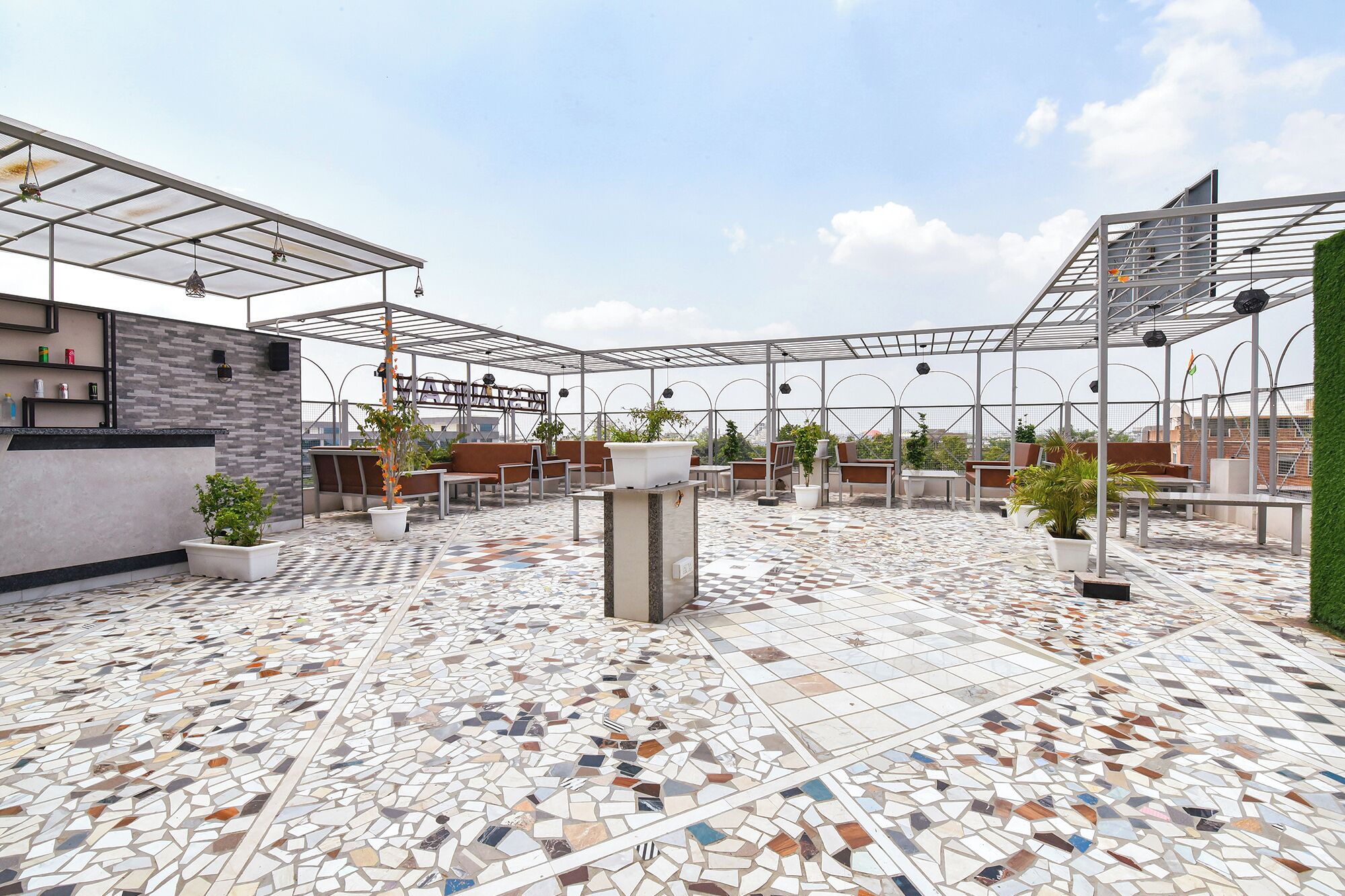 A rooftop terrace with a mosaic floor, seating areas, and potted plants.