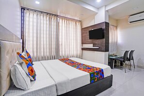 Une chambre d’hôtel équipée d’un lit, d’un bureau, d’une chaise, d’un téléviseur fixé au mur et d’un appareil de climatisation.