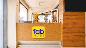 Una recepción con el rótulo de Fab Hotels, un ventilador de techo y un panel de madera en la pared.