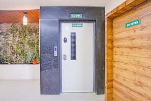 Une porte d’ascenseur avec un panneau indiquant « DÉFENSE DE FUMER », un autre panneau indiquant « POUSSER » et un panneau « ASCENSEUR » au-dessus.