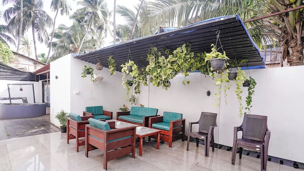 A patio with wooden furniture, hanging plants, and a tiled floor. - FabHotel Pontas Luxury Stay (Calangute)