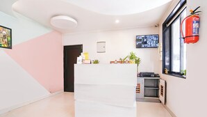 A reception area with a white desk, a fire extinguisher, a security camera, and a window with a view. - FabHotel Pontas Luxury Stay (Calangute)