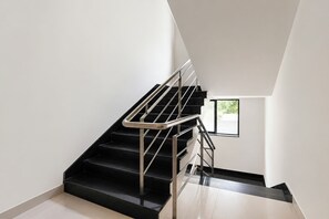 A modern staircase with metal railings and black steps leading to a landing.