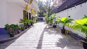 A narrow paved pathway flanked by potted plants and hanging lights, leading to a building entrance. - FabHotel Pontas Luxury Stay (Calangute)