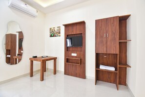 Una habitación con un armario de madera, un espejo, una mesa y una televisión.