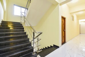 A staircase with metal railings, a wooden door, and a marble floor. - FabHotel Sattva Stays (Pune)