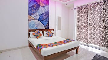 Un dormitorio con una cama, un cuadro abstracto grande, una cortina estampada y una ventana.