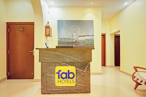 A hotel reception desk with a marble top and a 'fab hotels' logo, a wooden door with the number 106, and a large poster of a Ferris wheel. - FabHotel Cherish Stays (Ranchi)