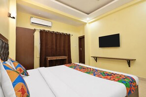 A hotel room with a bed, a TV, an air conditioning unit, and a curtain. - FabHotel Cherish Stays (Ranchi)