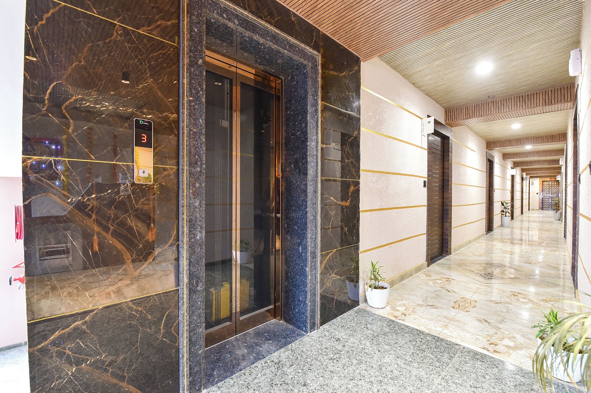 A hotel lobby with a marble floor, a reception desk, and a digital display.