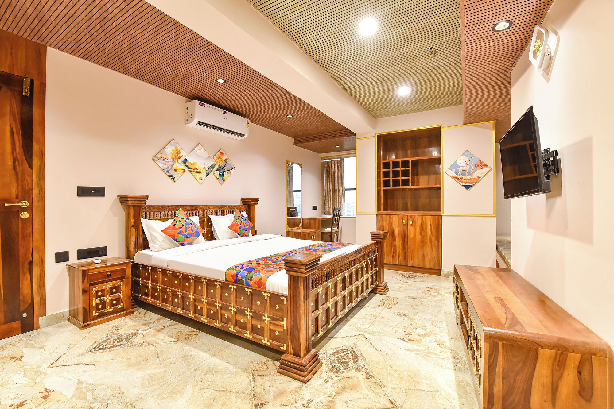 Un dormitorio con una cama de madera, un escritorio, un televisor y obras de arte en las paredes.