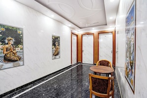 A hotel corridor with marble floors, wooden doors, and artwork on the walls. - Fabhotel Rc Residency (Noida)