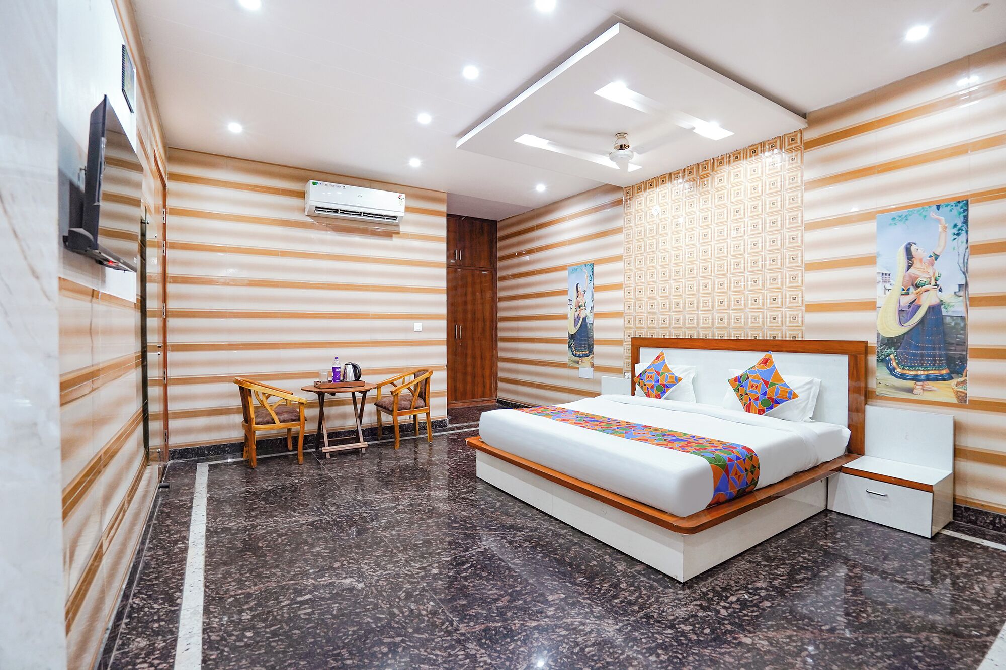 Quarto de hotel com cama, escrivaninha e cadeiras.