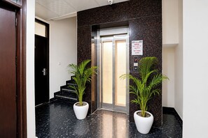 An elevator with a sign indicating a capacity limit of four people. - Fabhotel Luxora (Noida)
