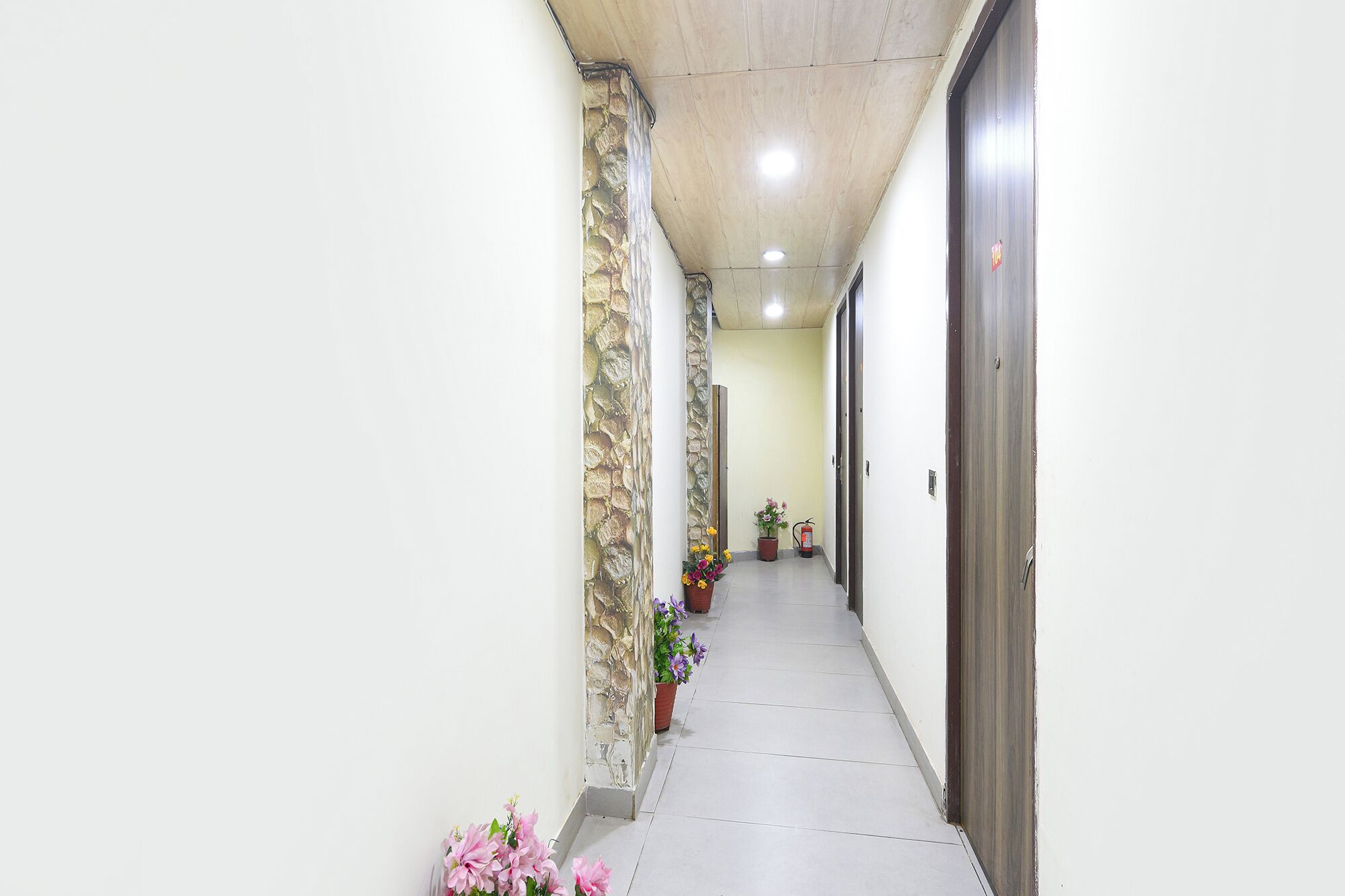 Um corredor com uma parede de pedra de um lado, soalho em azulejo e uma porta do outro.
