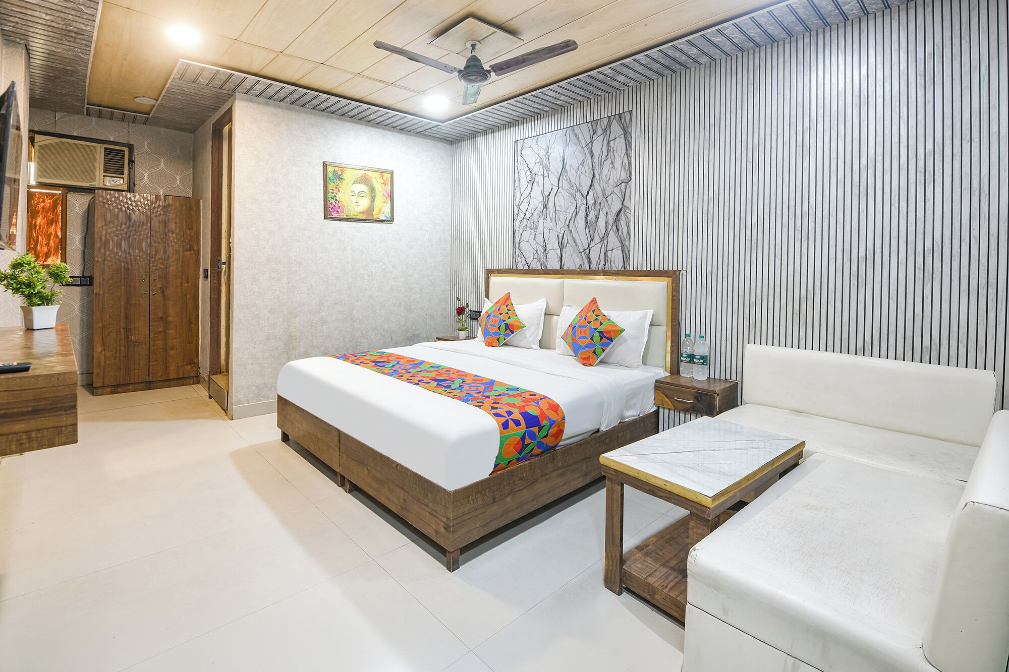 Quarto de hotel com cama, mesa de cabeceira e sofá.