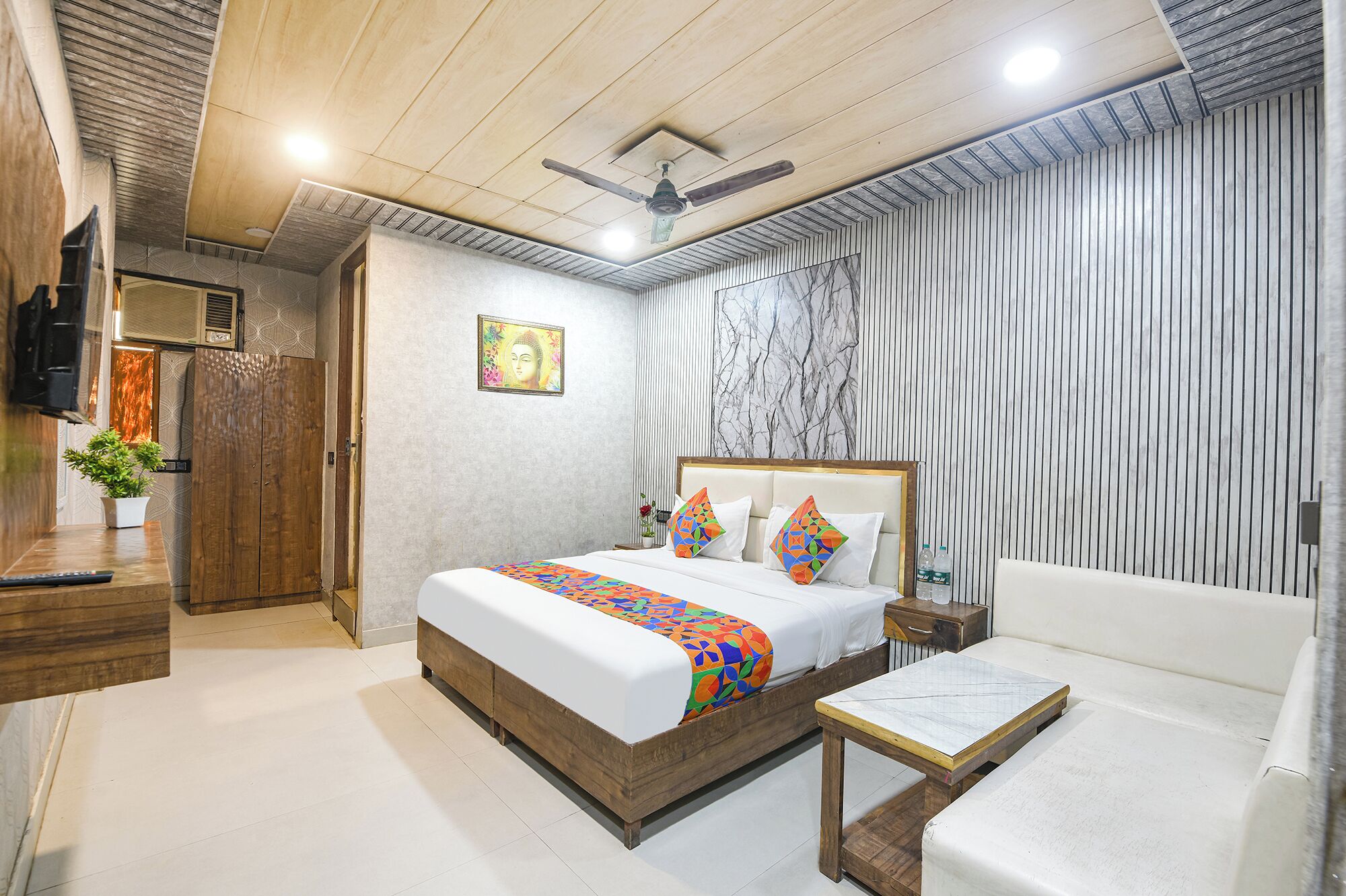 A hotel room with a bed, bedside table, and a seating area.