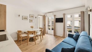 A modern living room with a blue sofa, wooden dining table, and chairs. - In the heart of Paris, new flat for 6, with AC (Paris)