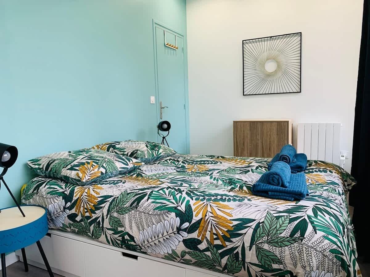 Una camera da letto con un letto, una sedia, una lampada a parete e un termosifone.