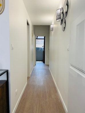 A hallway with a wooden floor, white walls, and a ceiling light fixture. - Beautiful 3-bedroom apartment / Porte de Versailles (Paris)