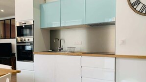 Une cuisine moderne avec des meubles blancs, une cuisinière en acier inoxydable et des meubles hauts bleu clair.